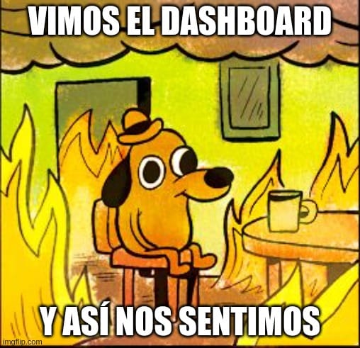 Meme del perro en llamas 'This is fine', modificado con texto en español que dice 'VIMOS EL DASHBOARD Y ASÍ NOS SENTIMO'. El perro está sentado tranquilamente tomando café mientras todo a su alrededor está en llamas.